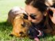 Eine junge Frau küsst ihren Hund, der auf dem Rasen liegt